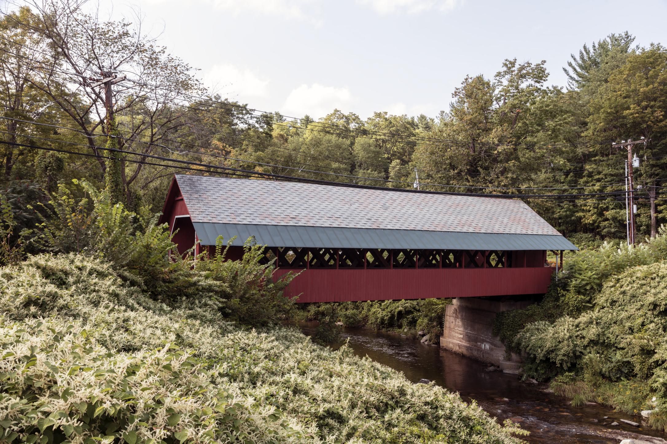 A classic Vermont covered wooden bridge spanning a stream amid autumn foliage