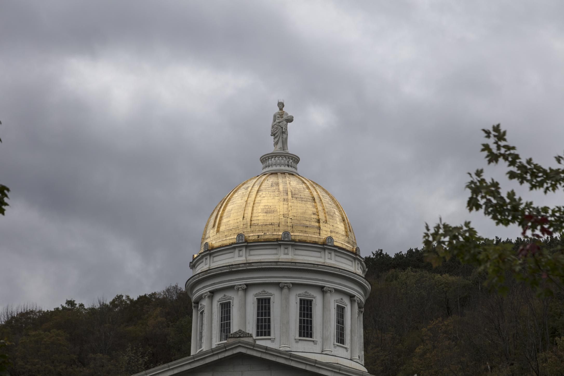 Vermont State House in Montpelier, a Greek Revival building with a golden dome, on a clear day